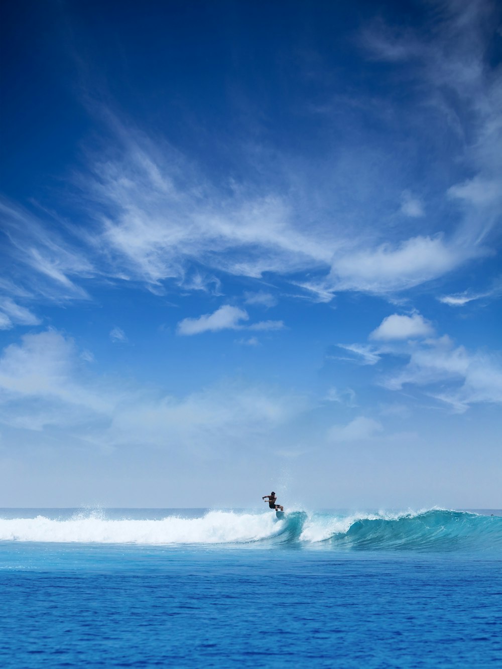 man surfing during daytime under white cloudy sky