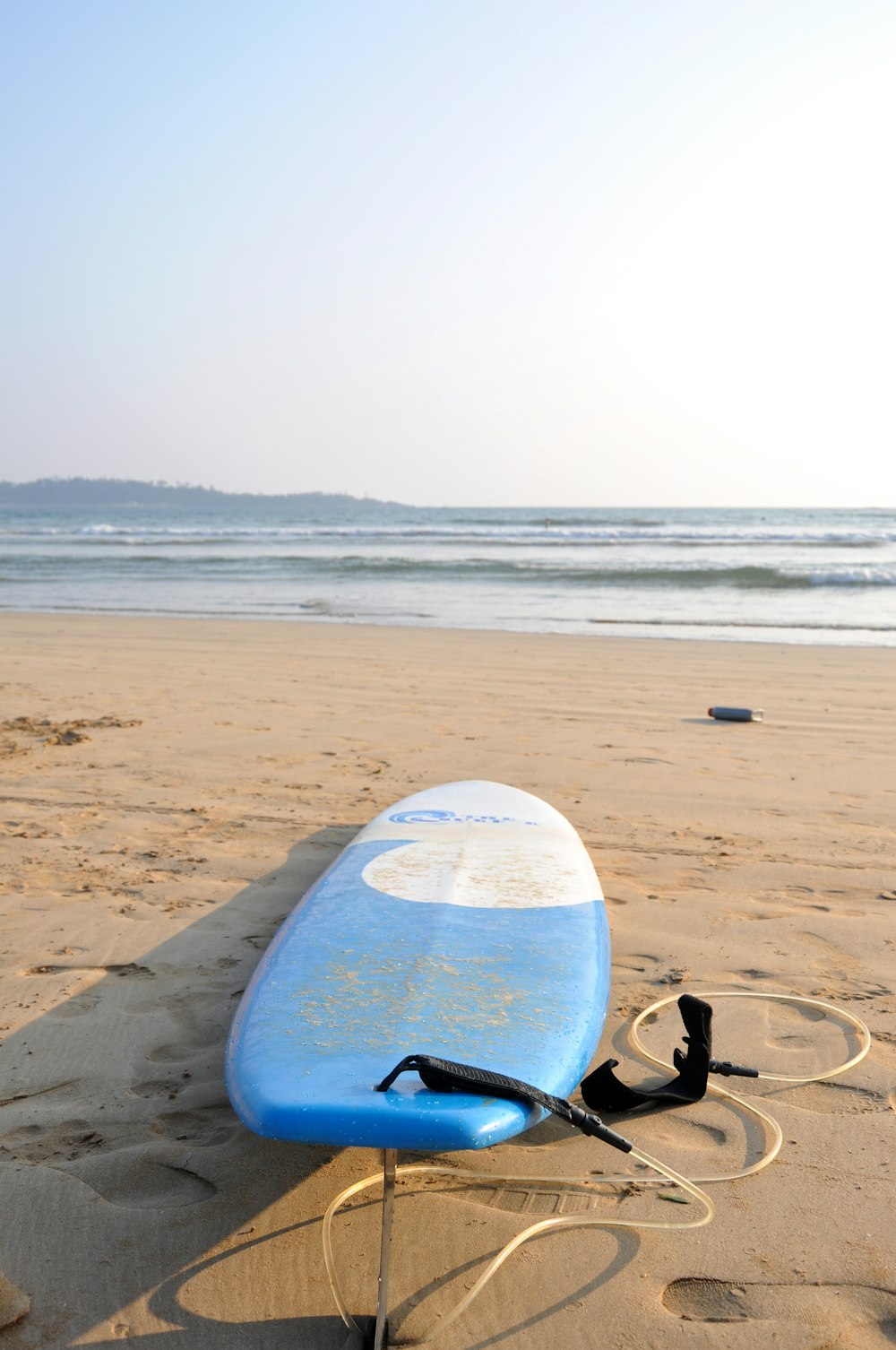 planche de surf bleue et blanche au bord de la mer