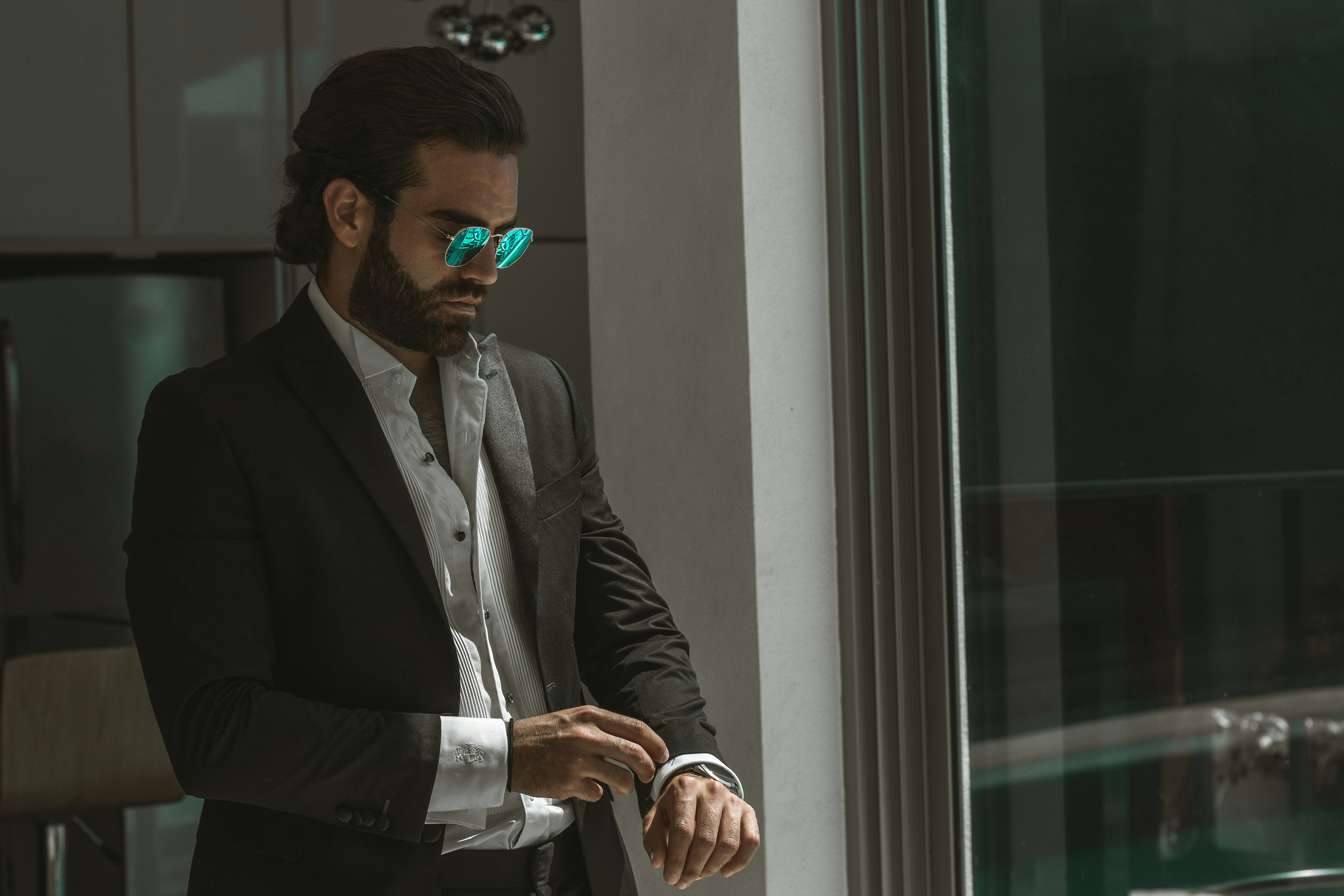 man wearing black coat over white dress shirt fixing his cuffs