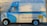 A vintage ice cream van painted blue and cream, featuring colorful ice cream illustrations on the sides. Writing on the van includes phrases like 'Traditional Ice Cream,' 'Antica Gelateria,' and 'Wholesome and Delicious.' The van is parked against a graffiti-covered wall.