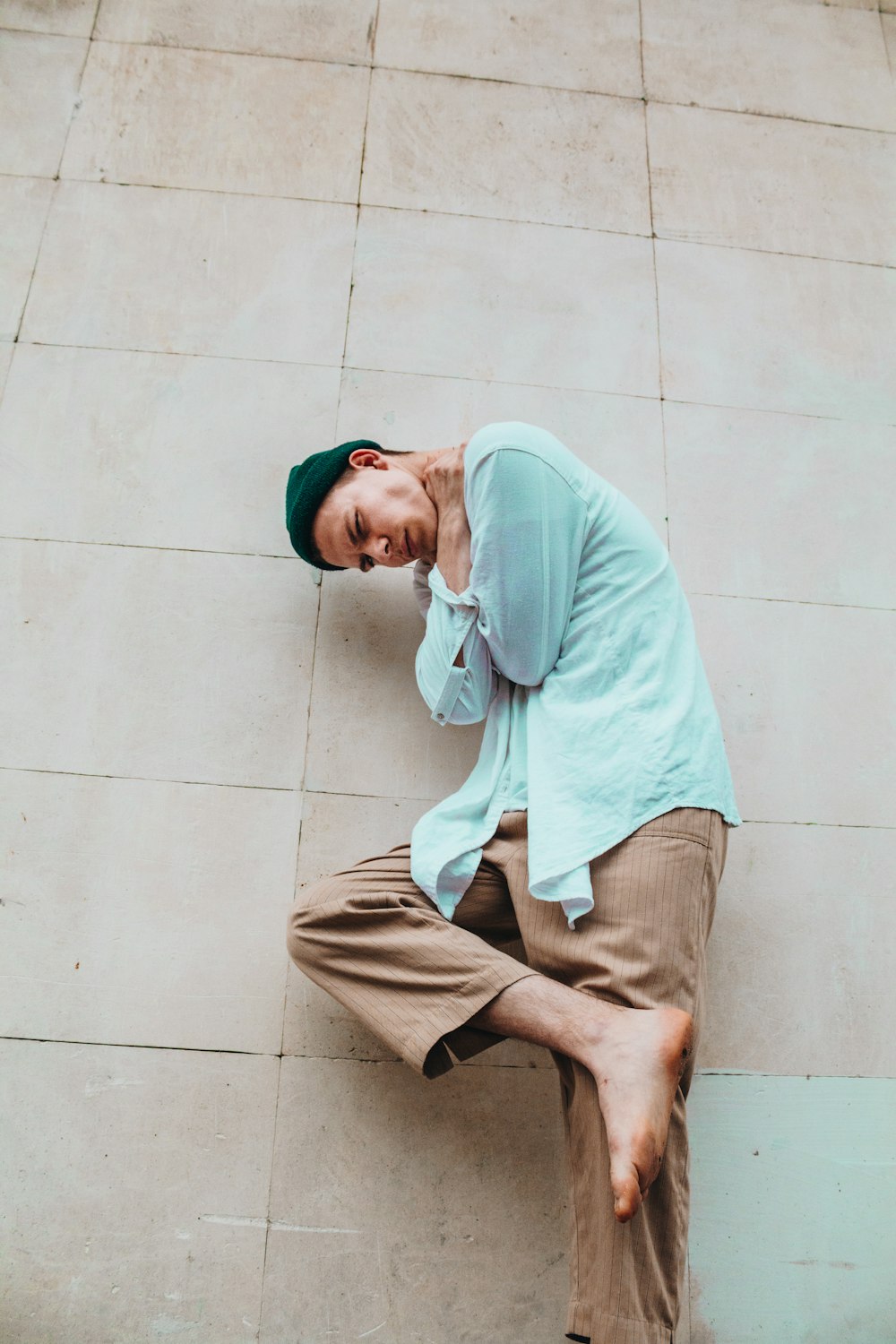 man in teal dress shirt leaning on wall