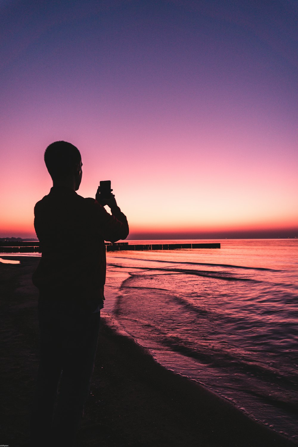 Silhouettenfotografie eines Mannes, der ein Android-Smartphone hält