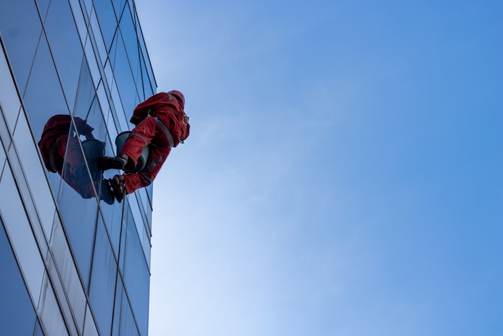 a man in a red suit climbing up the side of a tall building