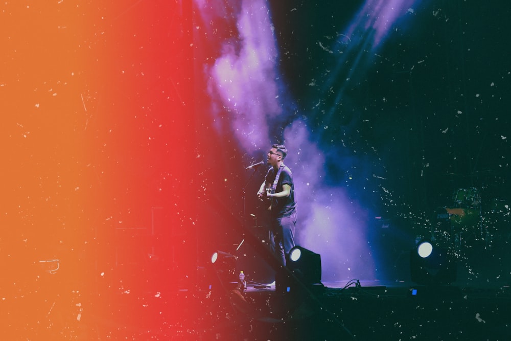 man playing guitar and singing on stage