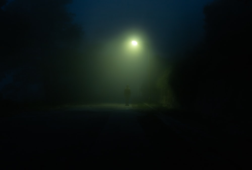 a person standing under a street light in the dark