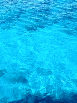 Vibrant shades of blue ripple across the surface of the water, creating a serene and calming visual effect. The texture is smooth with gentle undulating waves, suggesting a peaceful, natural environment.