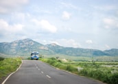 A luxury bus cruising on a highway surrounded by greenery.