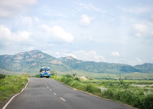 A comfortable passenger bus traveling on a highway surrounded by greenery.