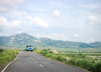 A scenic view of a bus traveling on a highway surrounded by nature.