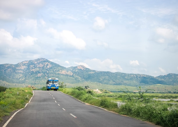 Image of a bus driving on a scenic highway surrounded by green hills.
