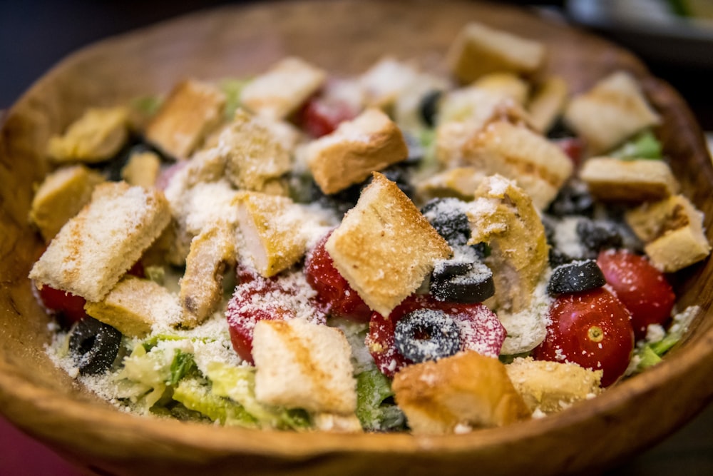 a wooden bowl filled with a salad covered in croutons