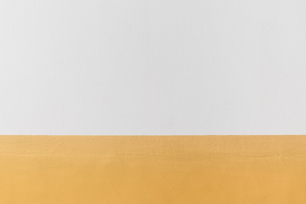 Una pared blanca y amarilla con un reloj en blanco y negro