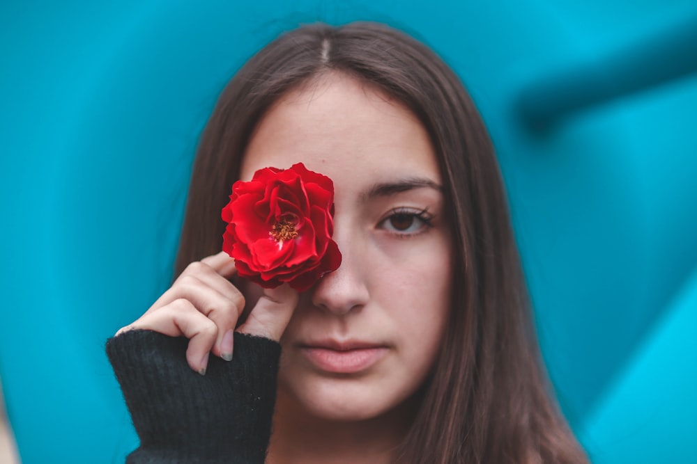 Femme tenant une fleur de rose rouge