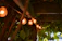 Warmly lit outdoor dining area with timber decking and soft glowing pergola lights at dusk.