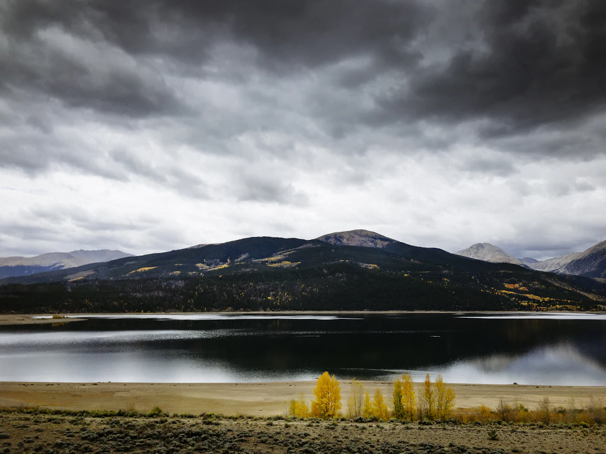 Storm clouds over a mountain and a lake at Twin Lakes, with yellow aspens on the near shore