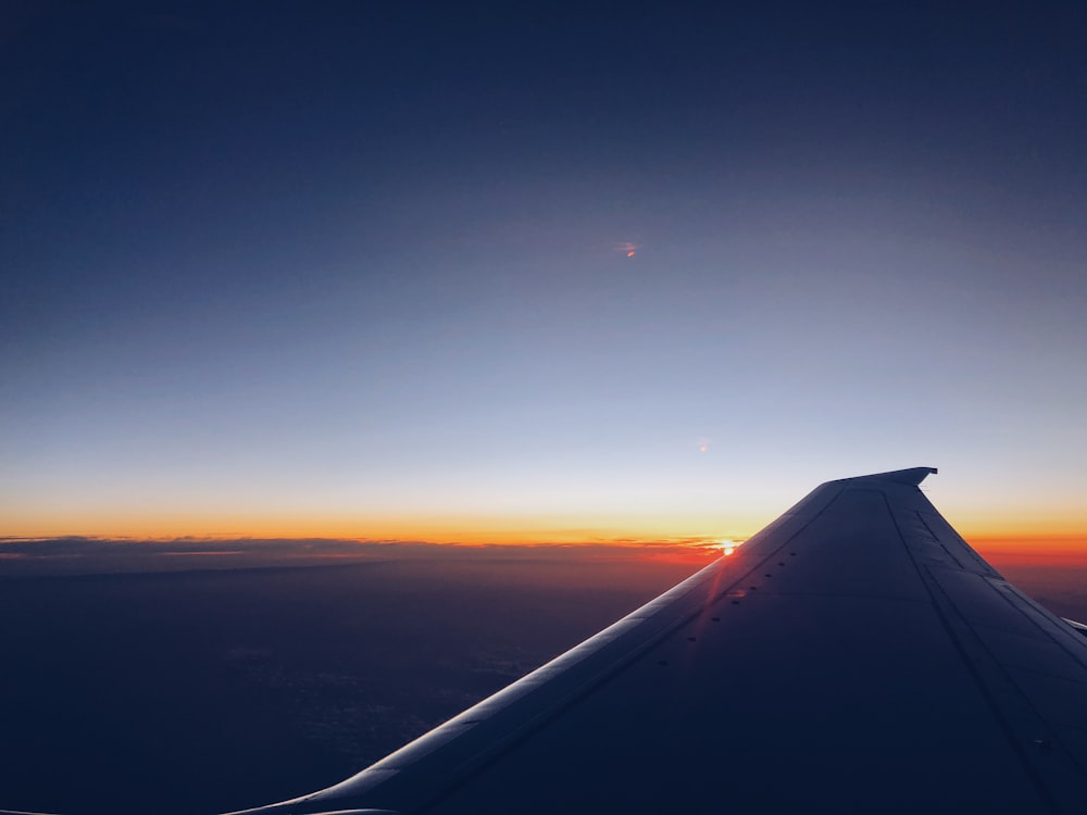silhouette photography of plane's wing during sunset