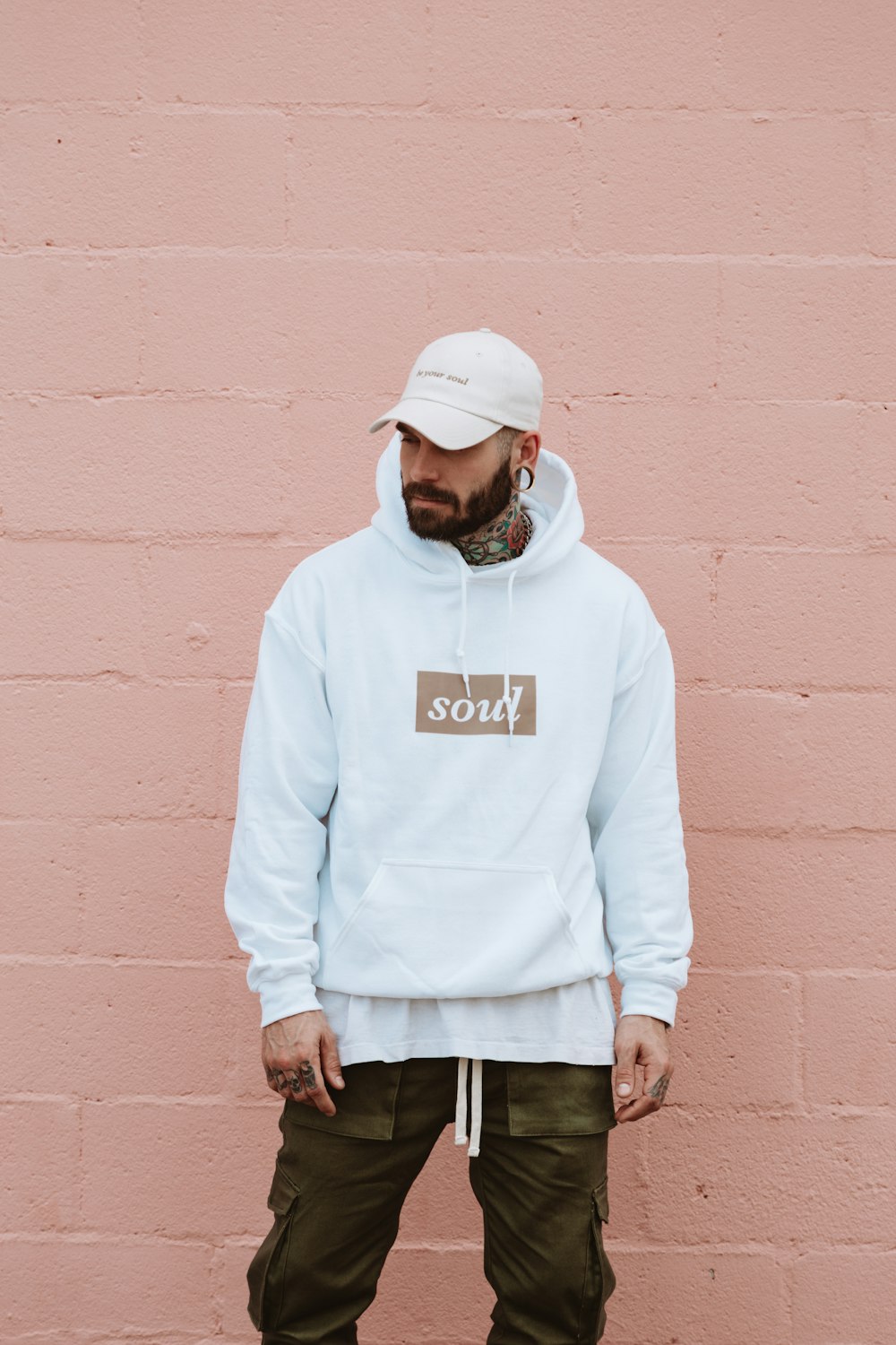 man wearing white pullover hoodie standing against the wall