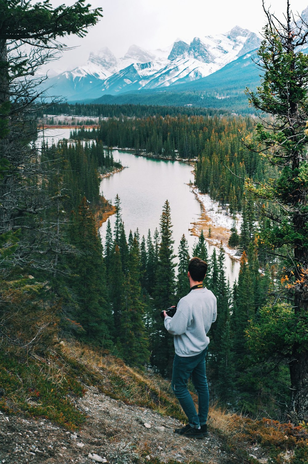 Mann im Pullover, der auf einer Klippe steht und den Fluss beobachtet