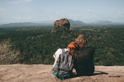 man and woman sitting beside cliff