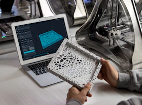 Close-up of a designer’s hands working on a tablet with 3D modeling software.