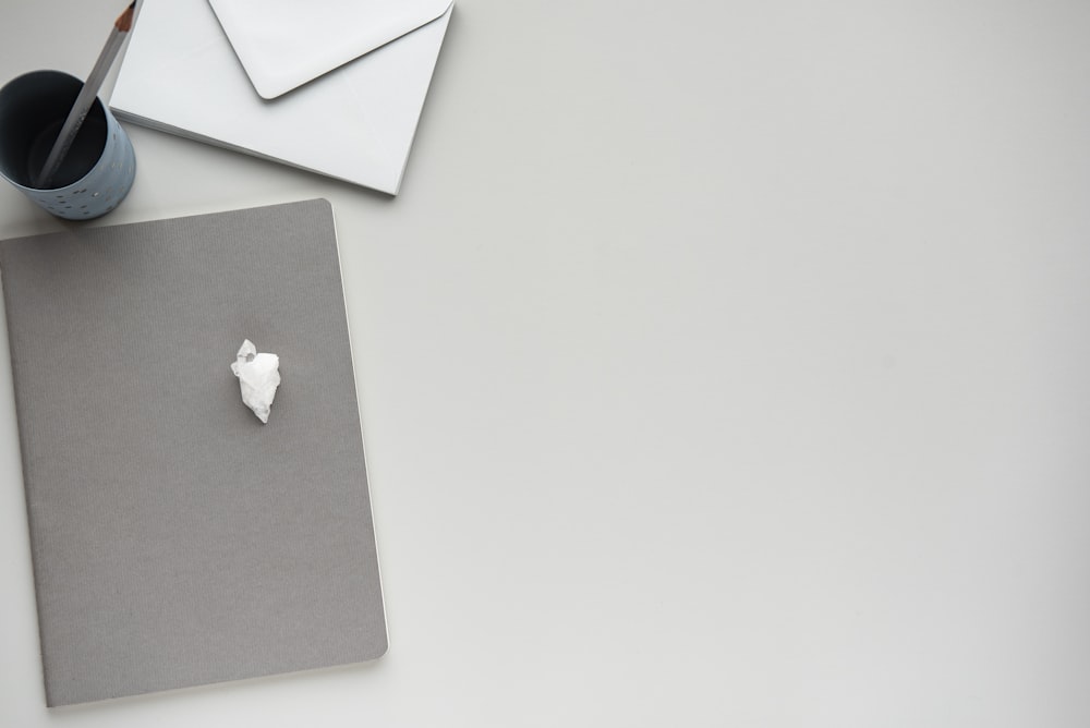 flat lay photography of gray pencil rack in between of envelope and gray board