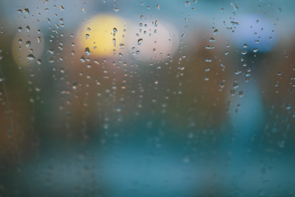 Regentropfen auf ein Fenster mit verschwommenen Gebäuden im Hintergrund