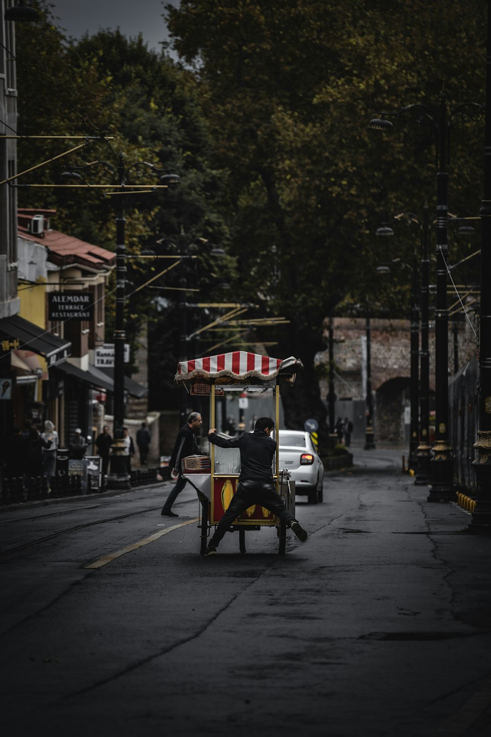 man pulling food cart in the middle of road