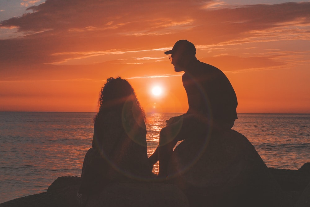 silhouette of woman and man near sea