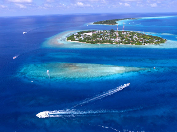An aerial view of a vibrant Caribbean island with colorful coral reefs and boats.