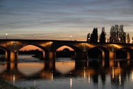 Sunset casting warm light over a newly completed bridge spanning a calm river.