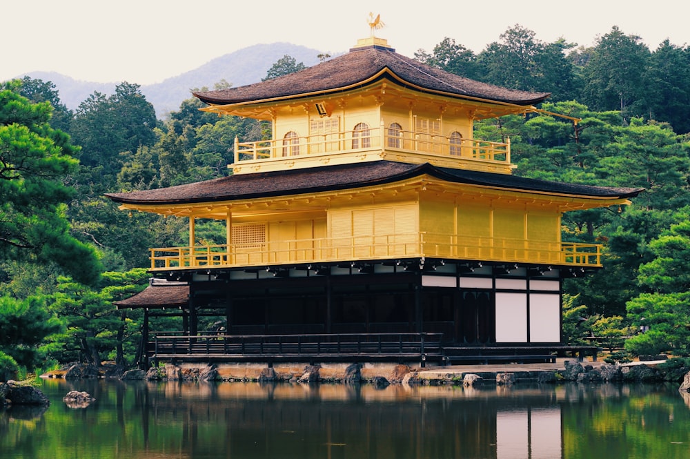 yellow tori building surrounded with trees and lake
