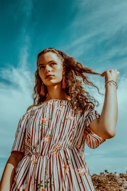 perspective and angle for photo composition,how to photograph a crazy portrait taken for a young red head girl showing the new autumn collection of dresses.; woman holding her hair standing on shore