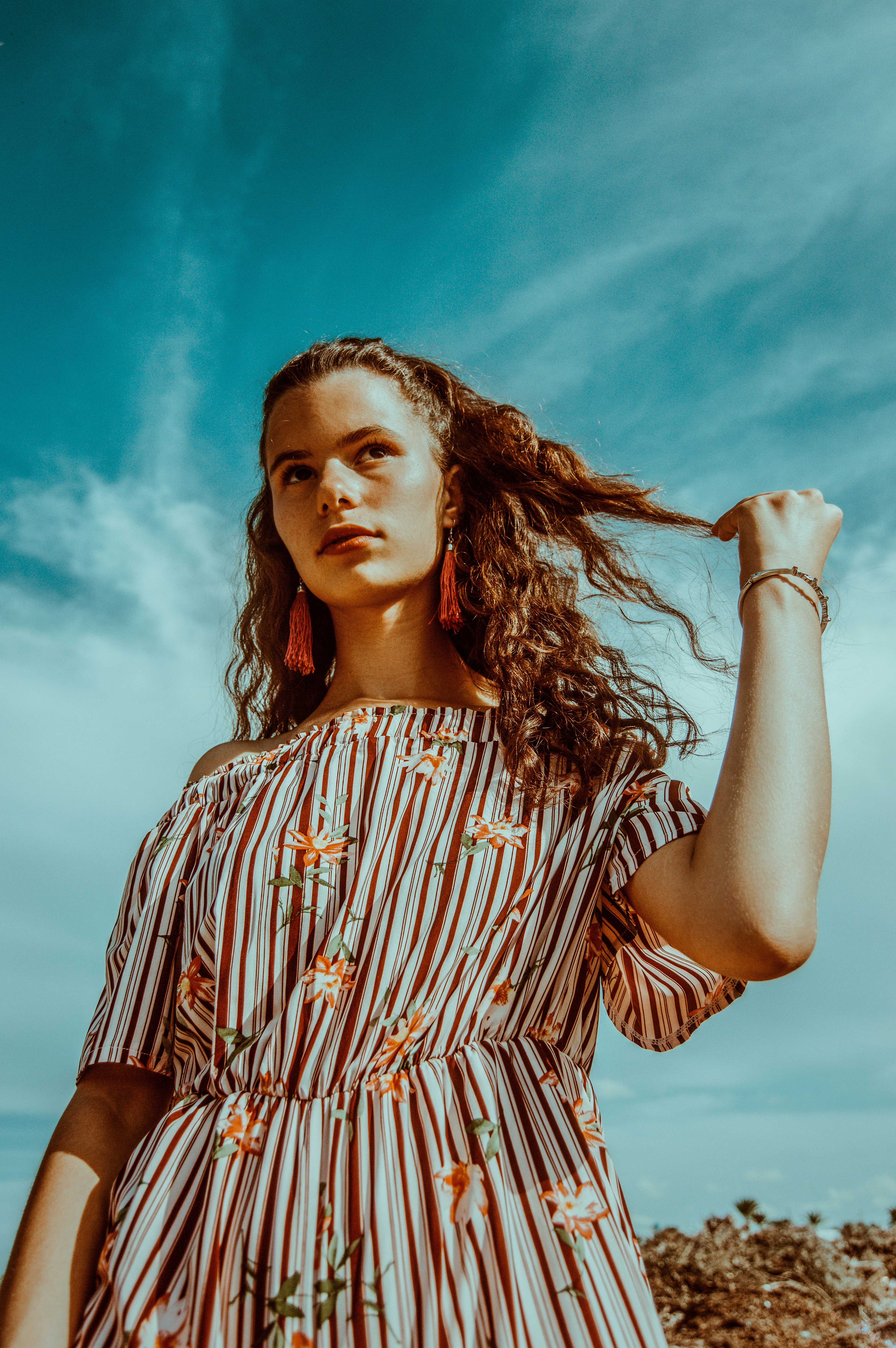 great photo recipe,how to photograph a crazy portrait taken for a young red head girl showing the new autumn collection of dresses.; woman holding her hair standing on shore