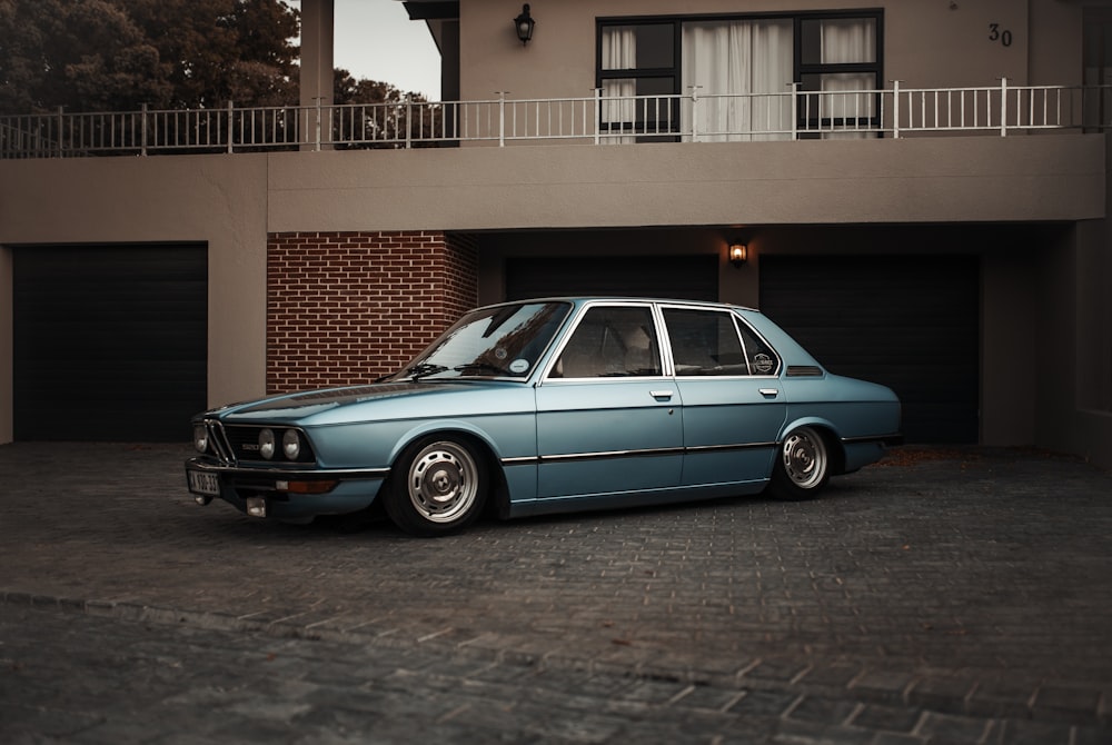 blue sedan parked beside house