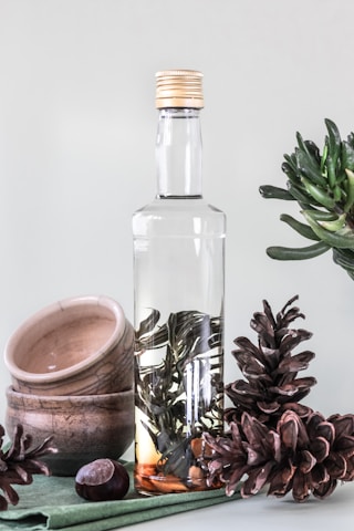 A serene image of amber bottles surrounded by green leaves and seeds.