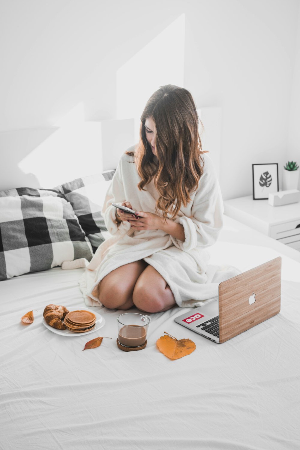 Frau auf Bett mit Smartphone in der Hand