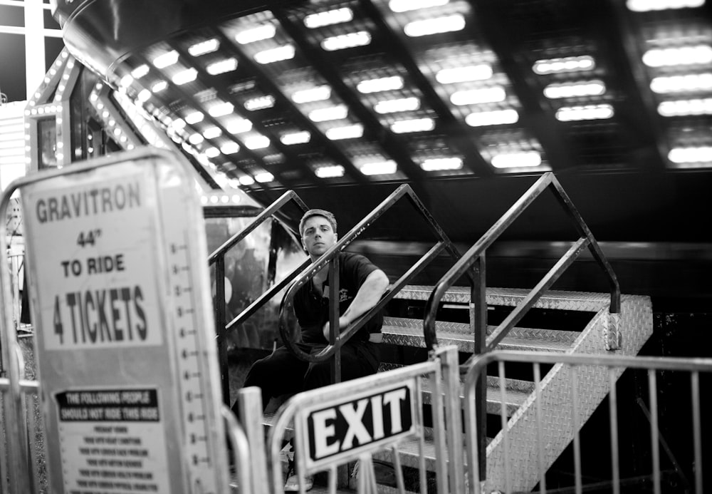 grayscale photography of man sitting on stair