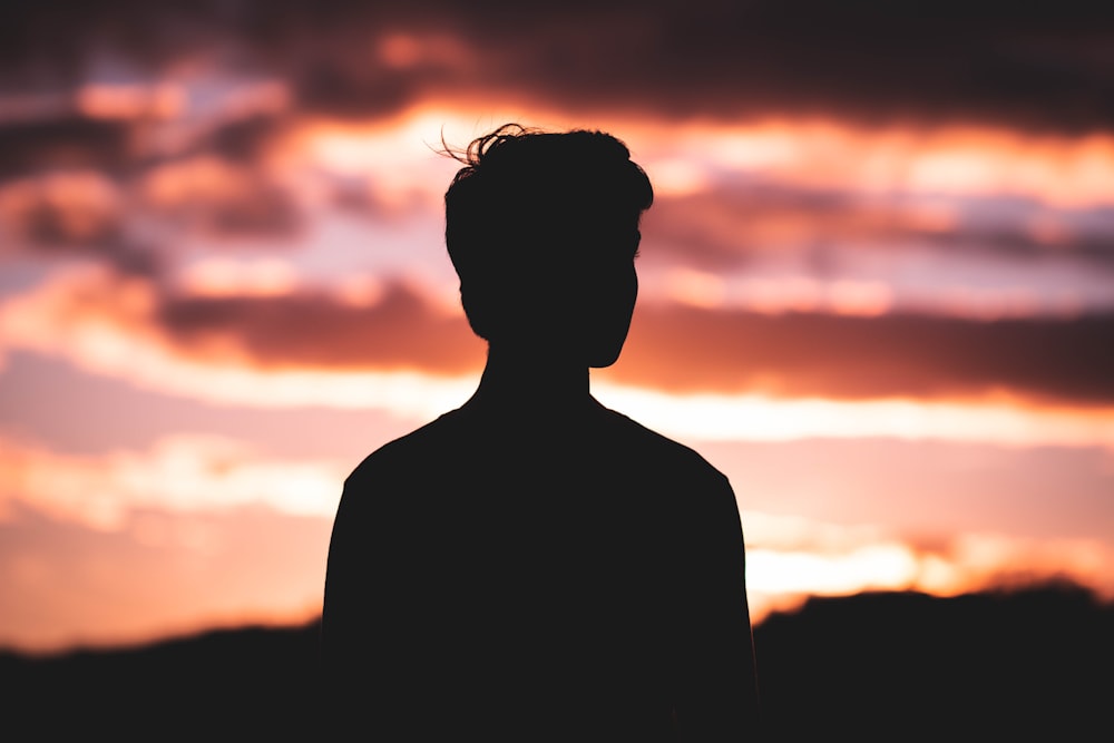 silhouette photography of man standing in front of red sky