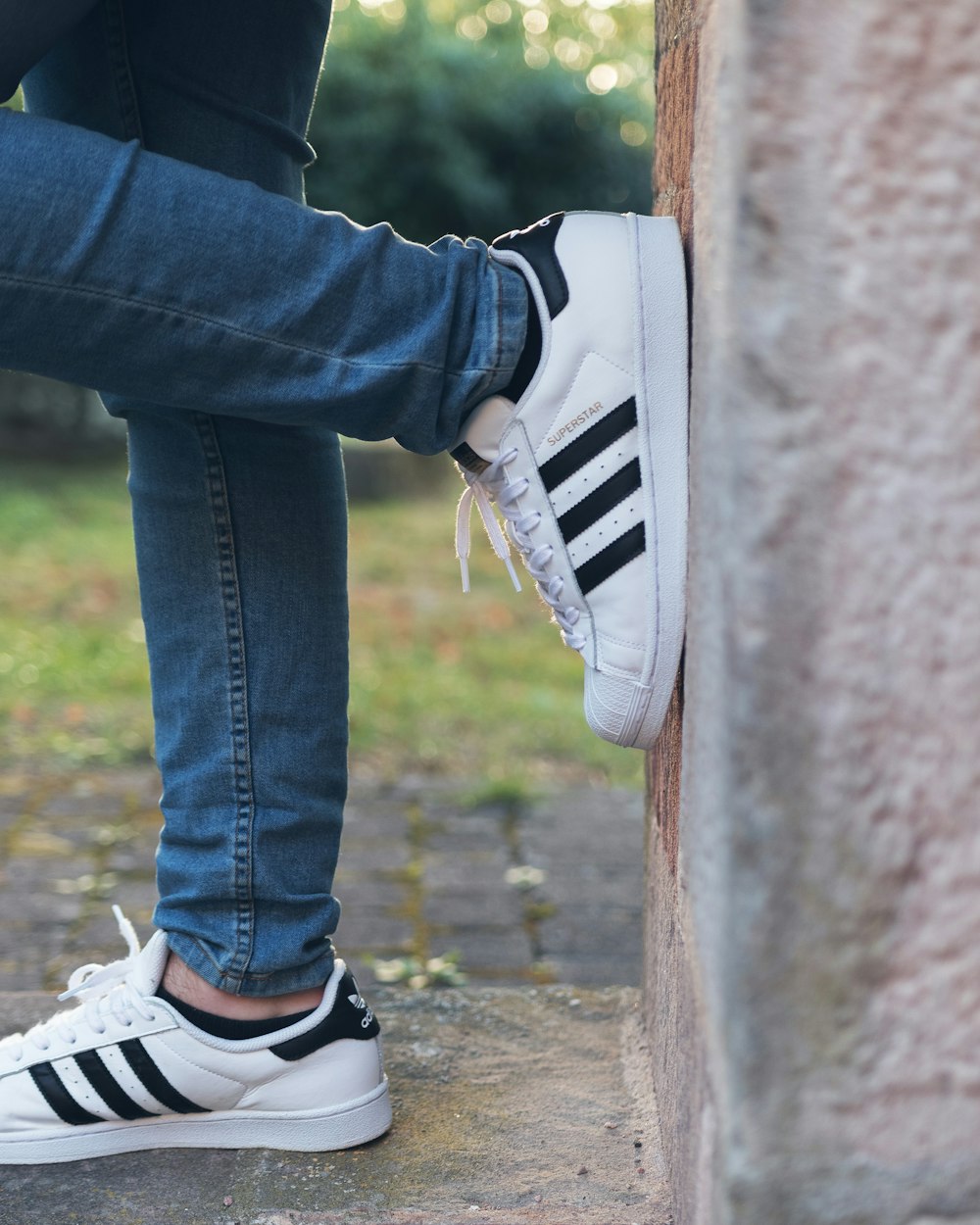 Person wearing white adidas Superstar while leaning on wall photo – Free  Grey Image on Unsplash