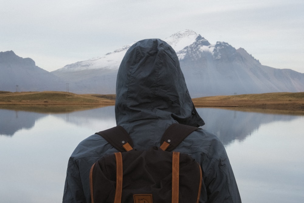 person with backpack standing near body of water during daytime