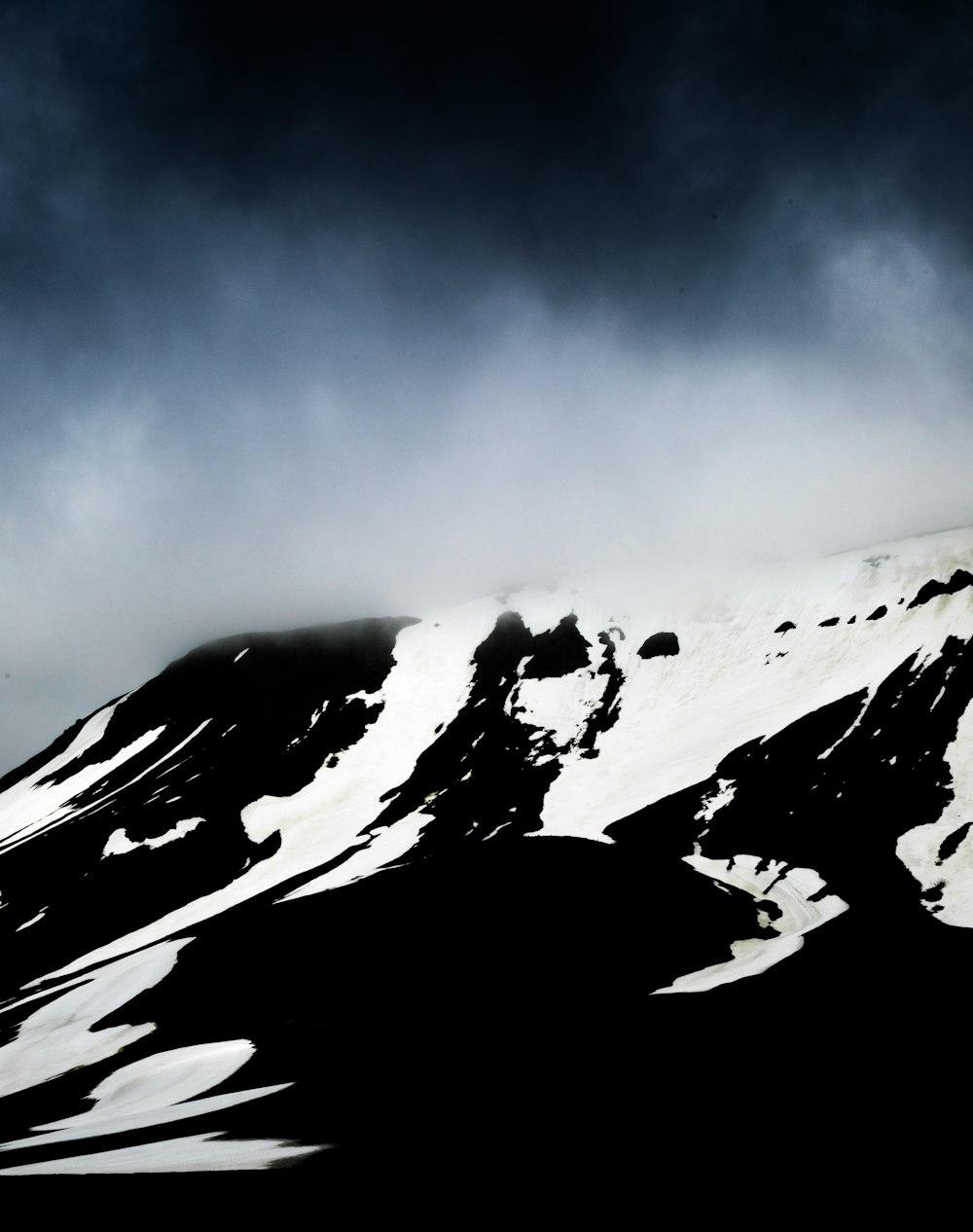 a mountain covered in snow under a cloudy sky