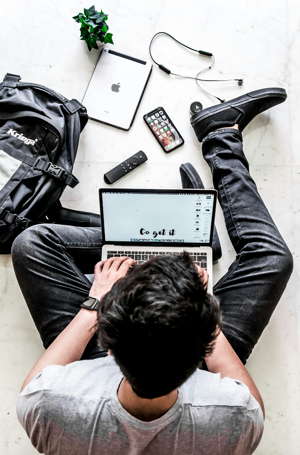 man using laptop while sitting on white surface