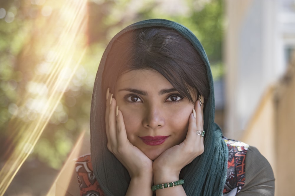 woman in green hijab with hands on hear face