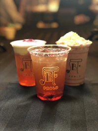 A variety of refreshing beverages in glass cups on a pink surface.