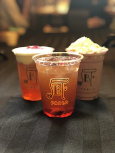 A variety of refreshing beverages in glass cups on a pink surface.