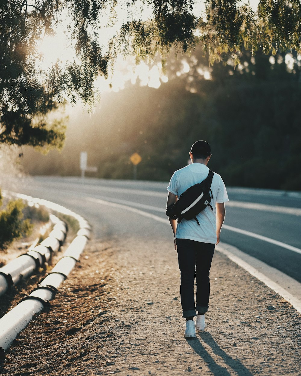 man walking beside road during orange sunset