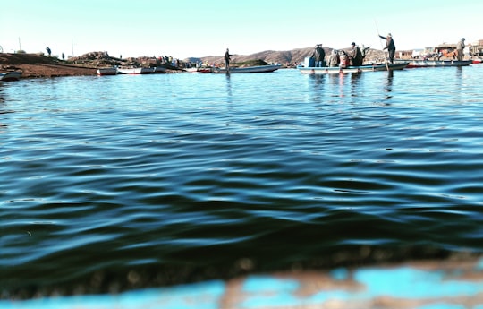 people riding boats on body of water during day in Puno Peru