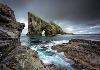 view of sea stacks and an islet further away whose peaks disappear into the clouds from across the water