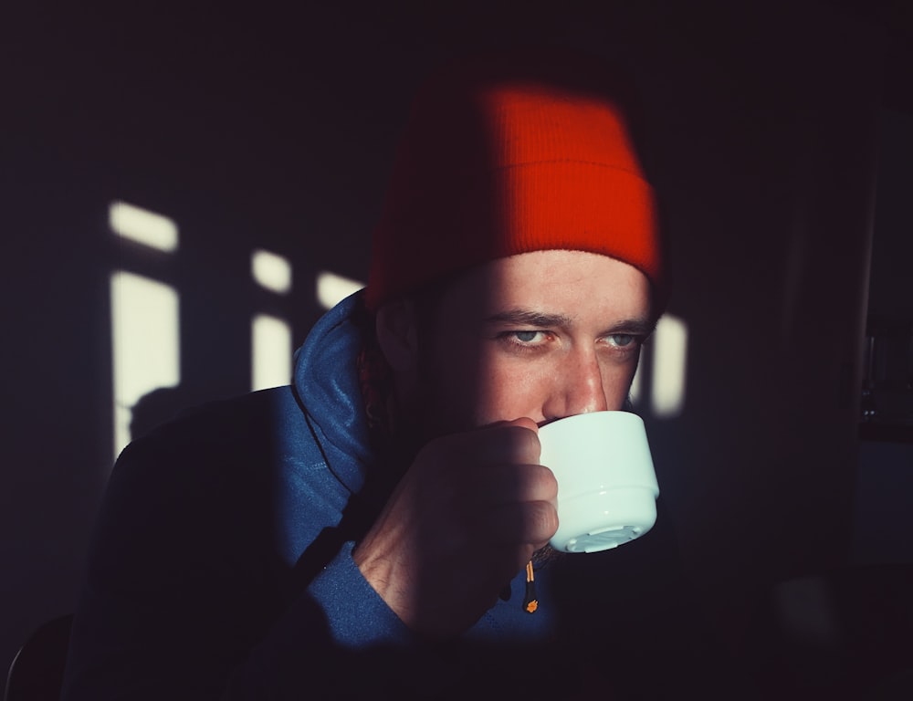 man in blue hoodie drinking from cup