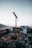 A sleek elmak flat top tower crane towering over a busy city construction site at sunset.